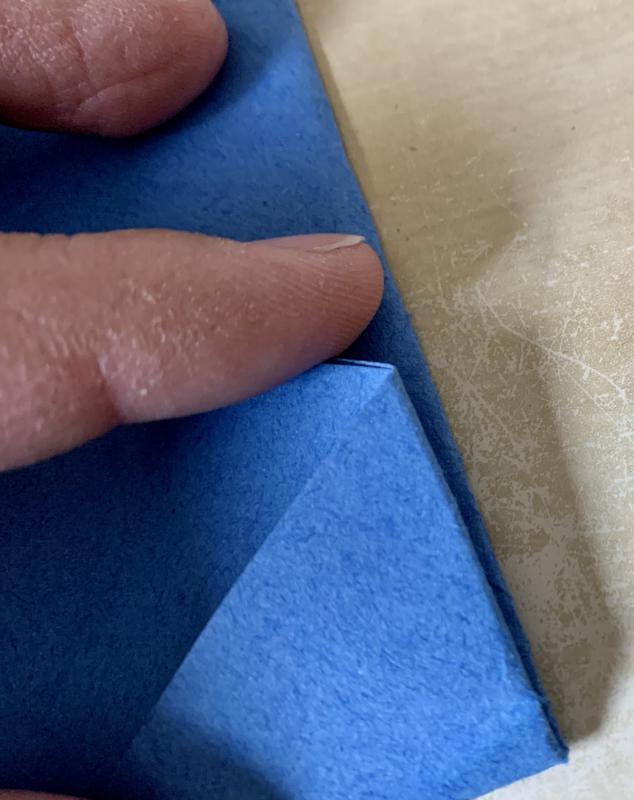 A close-up photograph of the resulting fold. We see that the two sides of the fold line up. The author's index finger is holding the paper down.